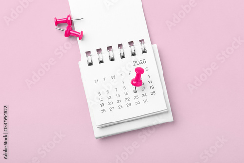 Calendar with pinned date on pink background, business reminder or appointment, holiday planning