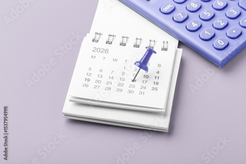 Pinned date on calendar 2026 with calculator on pastel purple background, financial reminder, tax payment, budget planning