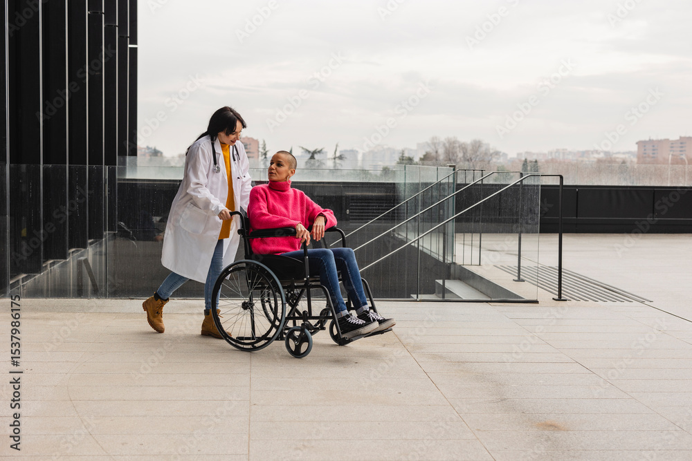 Obraz premium Doctor pushing patient in wheelchair outside hospital building