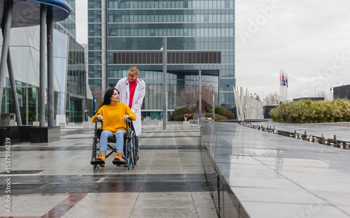 Doctor pushing patient in wheelchair outside hospital