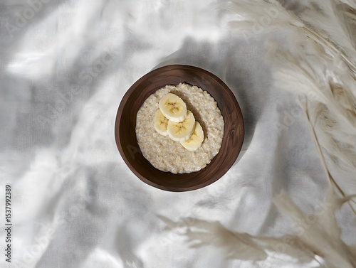 Simple bowl of oatmeal topped with neatly sliced banana, viewed from above.