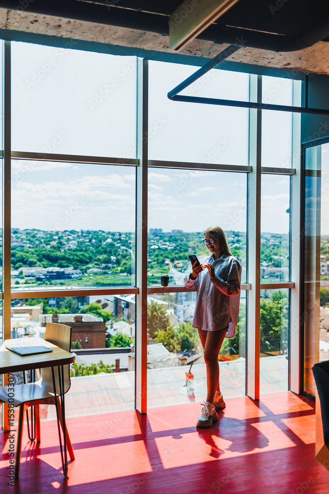 A stylish individual confidently using a smartphone while situated in a modern office space that beautifully overlooks a scenic view, creating an inspiring and productive atmosphere for work A stylish individual confidently using a smartphone while situated in a modern office space that beautifully overlooks a scenic view, creating an inspiring and productive atmosphere for work
