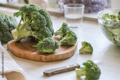Fresh broccoli florets on a wooden cutting board with a knife ready for cooking highlighting healthy eating