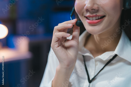 Smiling operator talking on headset in call center at night