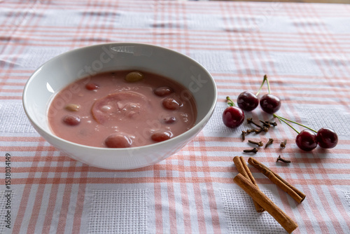 chilled cherry soup with fresh cherries and spices on checkered tablecloth side view