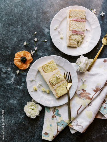 Two cake slices with flowers and gold forks on floral napkin