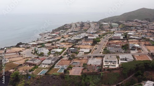 Descending aerial dolly shot of cleared residential lots in the oceanfront Sunset Mesa neighborhood after the Palisades Fire in Malibu, California. 4K