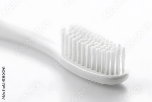 Close up shot of a white toothbrush with soft bristles on a white surface in a well lit environment