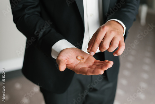 Groom Holding And Inspecting Wedding Rings