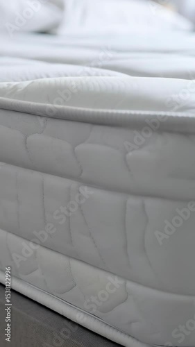 Close-up vertical shot of a plush, white mattress with quilted pattern and bedding, offering comfort and support.
