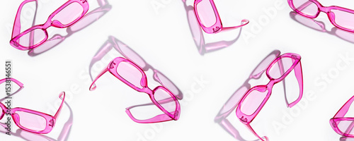A pattern of stylish pink plastic sunglasses with transparent glass on a white background