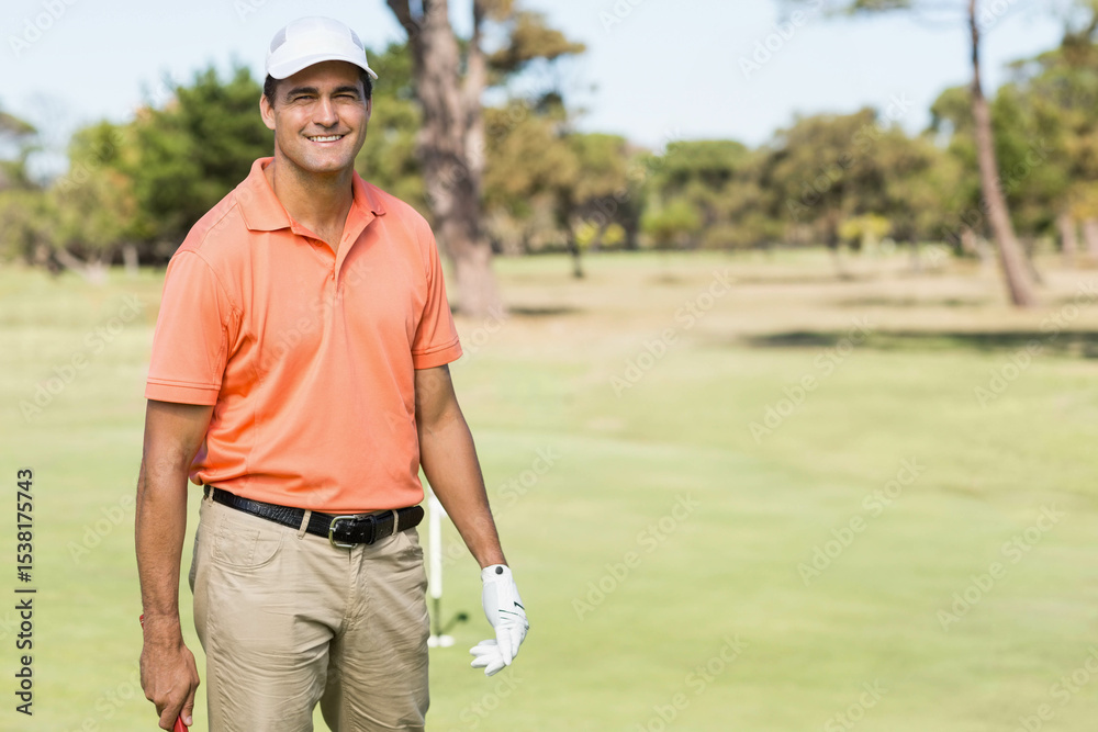Obraz premium Golf club leaning beside flagstick marking hole on green near fairway with pine trees