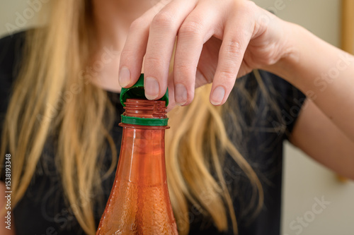 Unscrew the cap of a plastic bottle of sweetened carbonated drink