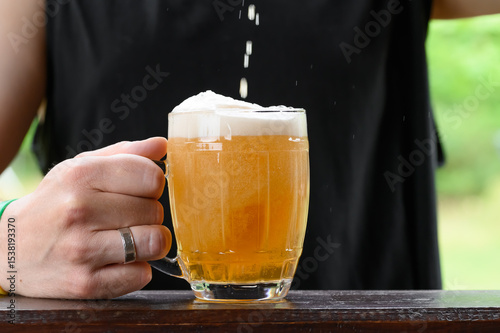 Golden beer poured into a glass beer mug, beer with foam