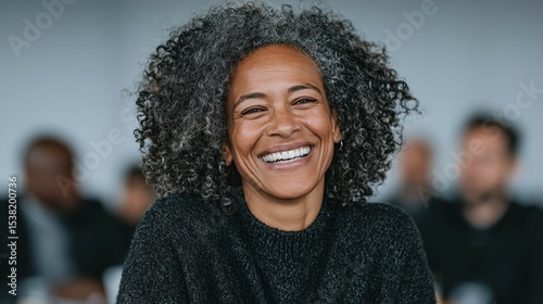 Smiling woman with gray hair in a meeting or conference setting.