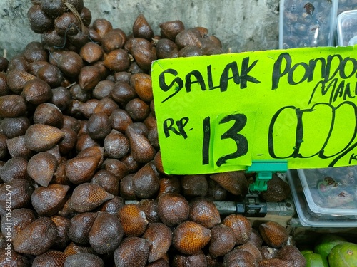Snake fruit for sale at a traditional Indonesian market with handwritten price tag. Tropical exotic fruit with scaly skin texture and sweet-sour flavor.