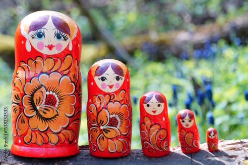 Wooden nesting dolls stand in a row in the forest.