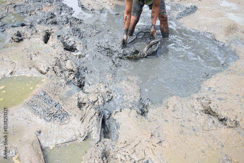 Worker working in the mud to clean the soil with a shovel