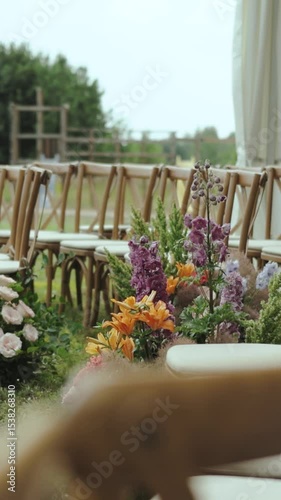 Elegant wooden chairs with vibrant flowers create a beautiful scene for a romantic outdoor wedding celebration. Vertical video