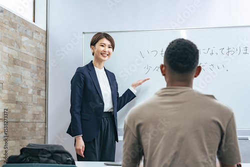 Fotografie A female teacher teaches business terms to a black man at a Japanese language school