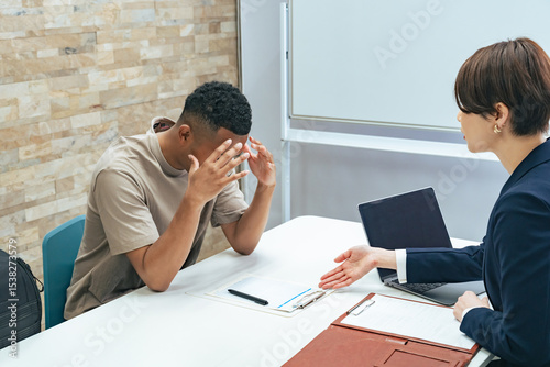 A Japanese female staff member interviewing a troubled black man
