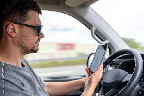 Driver looking at phone. Smartphone navigation in car. Man holding device.