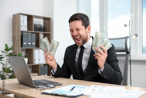 Photos Happy greedy banker with dollar banknotes at table in office