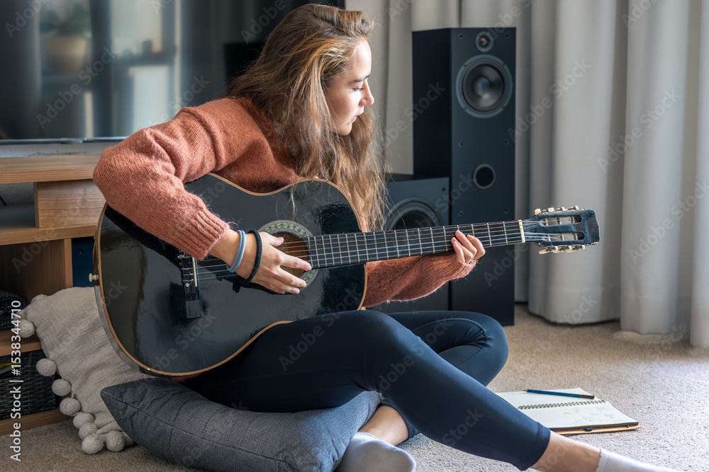 Fototapeta premium Teenage girl learning to play guitar at home. Girl composing music. Guitar.