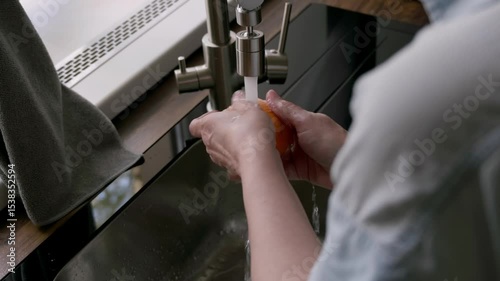 close-up of person washing a fresh ripe orange