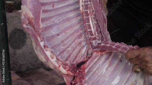 close up of a man's hand cutting meat with a knife