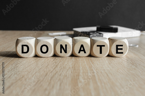 Wooden cubes with the inscription - DONATE Beautiful wooden table, black background. Info concept.