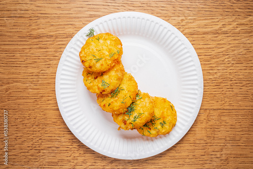 Savory golden fritters sit on a white plate, garnished with fresh herbs, inviting culinary delight