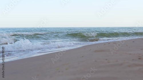 Waves break gently on a sandy beach, with the vast expanse of the sea and a clear horizon under a pale sky. This is likely the Black Sea coast of Ukraine.