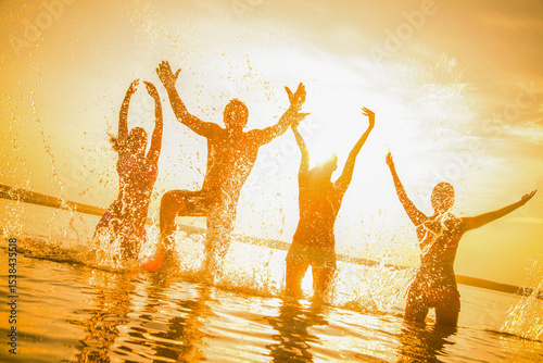 group of young people happily jump and splash in the sea at sunset Silhouettes.