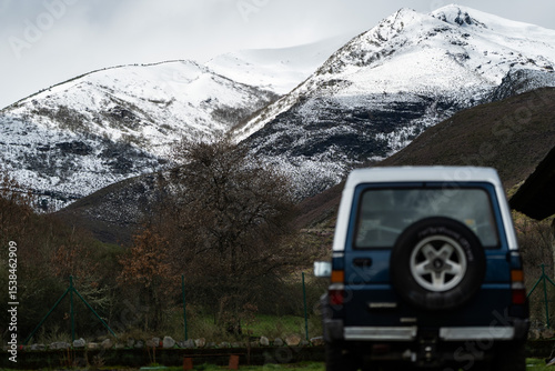 Off-road vehicle parked near snowy mountain range, embarking on winter adventure