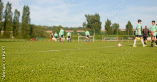 A group of enthusiastic and young aspiring soccer players is diligently training on a wellmaintained field, actively engaging in various drills and exercises beneath a bright and clear sky