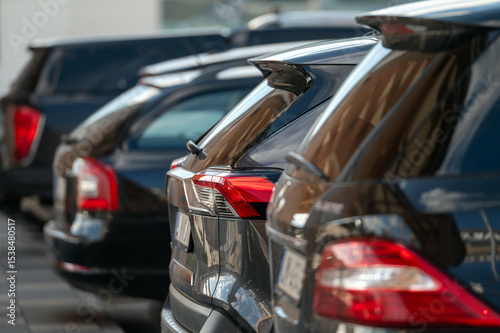 Rows of black vehicles parked in a sunny urban setting during late afternoon hours