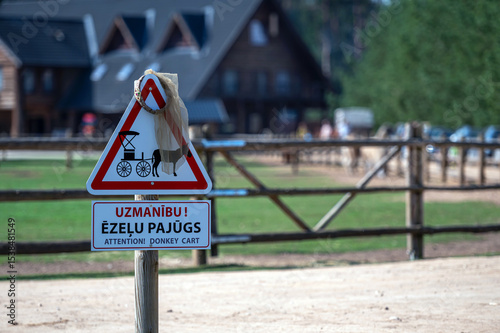 Warning sign for donkeys near a stable in a rural setting on a sunny day