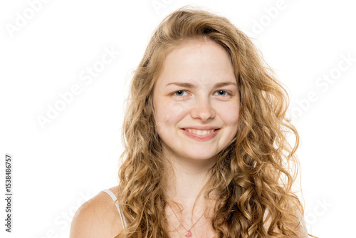 Smiling young woman with long curly blonde hair and freckles, no makeup. Close-up portrait on white background