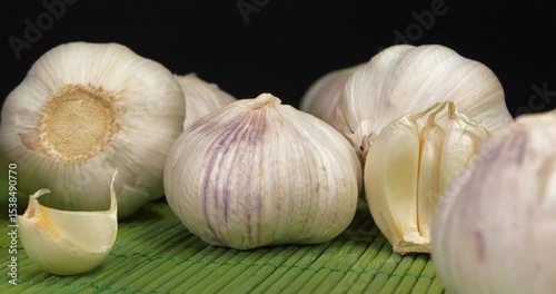 Garlic rotates on black background. Garlic, Allium sativum, species of bulbous flowering plants in genus Allium. Garlic - very healthy product with many beneficial properties for health
