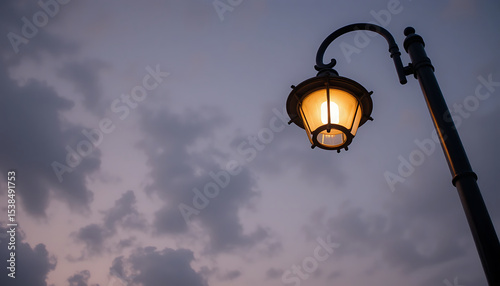 Street lamp illuminating the evening sky with clouds at dusk in a quiet neighborhood