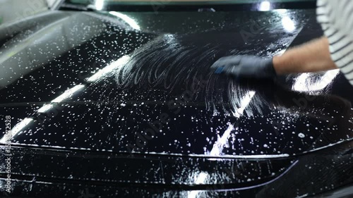 Worker clean car body with blue clay for cleaning before applying protective layer or coating to auto