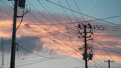 電柱とたくさんの電線の背景に夕焼けの空