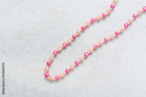 Overhead view of pink vintage necklace on marble jewelry holder, top view of vintage pink beaded necklace on a white background