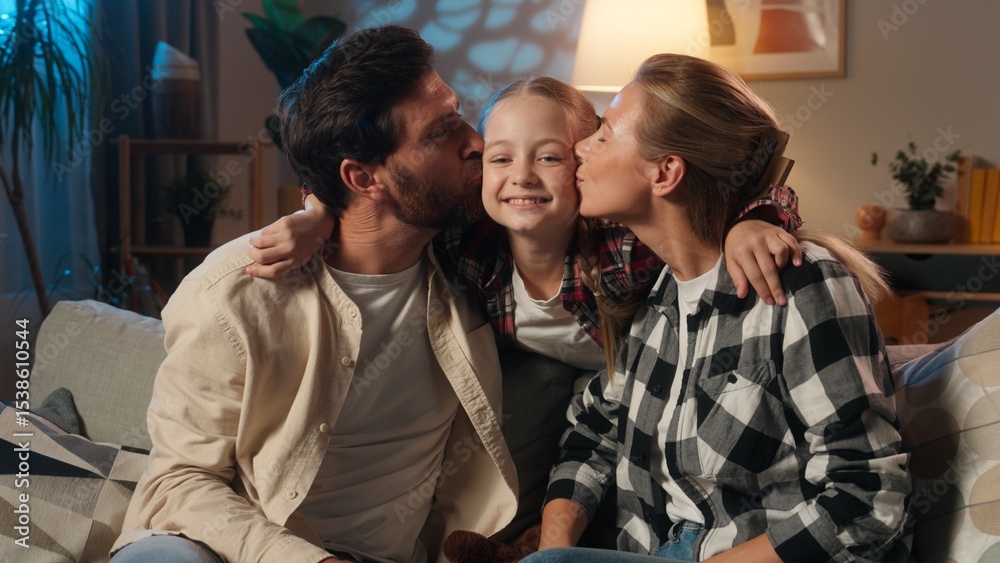 Obraz premium Caucasian happy family at home parents on sofa in evening talking surprised smiling about suddenly daughter child play jumping from behind couch playful kid mother and father kissing girl on cheeks
