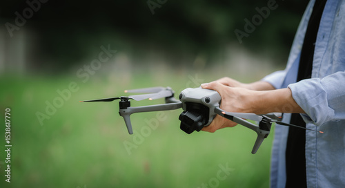 A hand operates a drone controller, with the drone hovering blurred in the background, suggesting aerial photography or exploration.