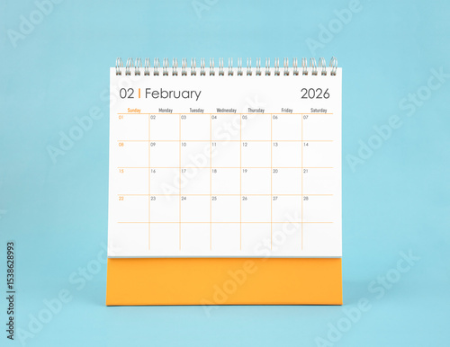 February 2026 white desk calendar on blue color background. Planning and goals concepts.