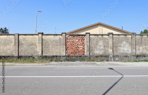 Wallpaper Mural Grunge boundary wall with the central part peeled with bricks exposed. Barbed wire on top  Roof, sky and street light on behind, Street in front. Background for copy space. Torontodigital.ca