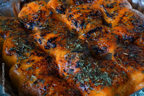 Close-up of cheesy mentai dimsum with torched sauce and herb garnish in an aluminum foil tray, ready to serve