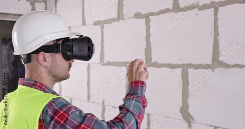 Engineer with headset measures wall width during work process. Professional in virtual reality glasses estimates size of room and calculates required values